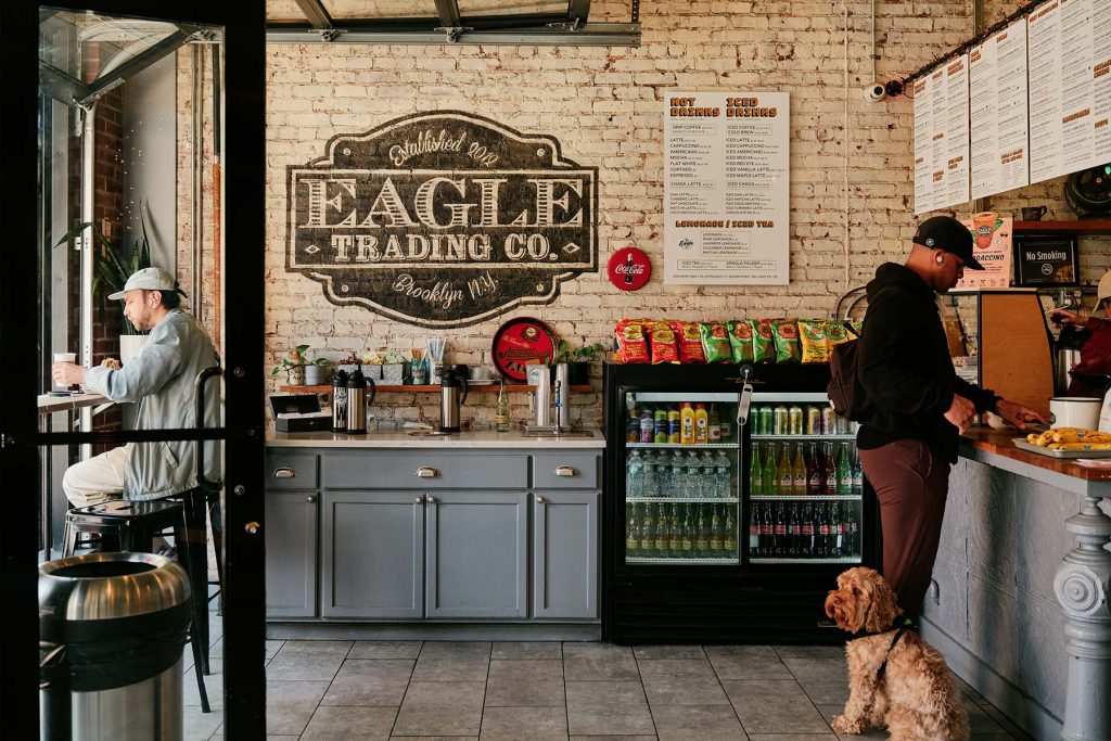 Greenpoint, Brooklyn. Eagle Trading Company cafe. Inside of cafe with person and dog at the counter ordering.