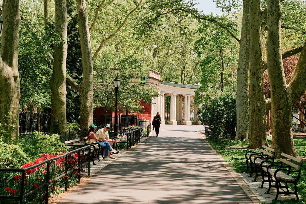 Greenpoint, Brooklyn. McGolrick Park in Greenpoint with greenery and red flowers in bloom.
